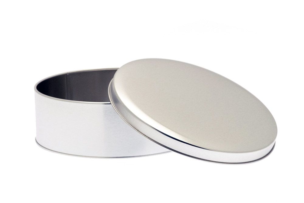 Boîte à biscuits ronde ouverte en métal couleur argent avec couvercle amovible, debout sur fond blanc.