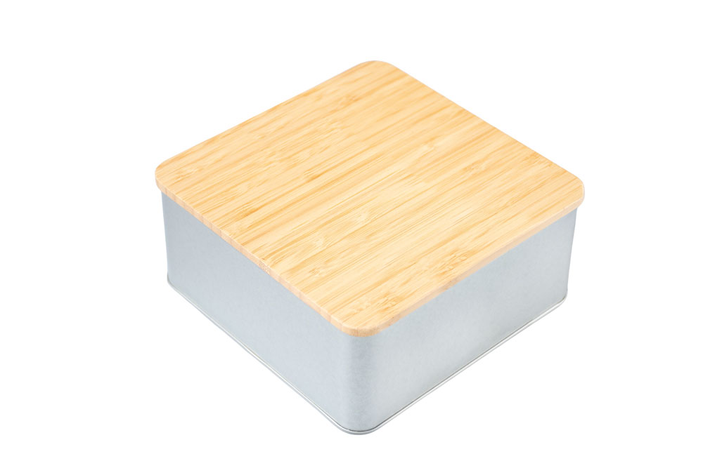 Boîte carrée fermée en métal couleur argent avec couvercle en bambou emboîtant, fond neutre.
