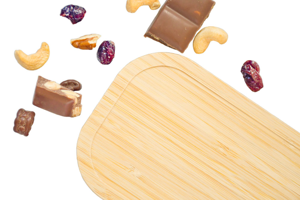Couvercle en bambou durable comme pièce de rechange pour boîte-repas en fer blanc, entouré de mélange de fruits secs et de chocolat