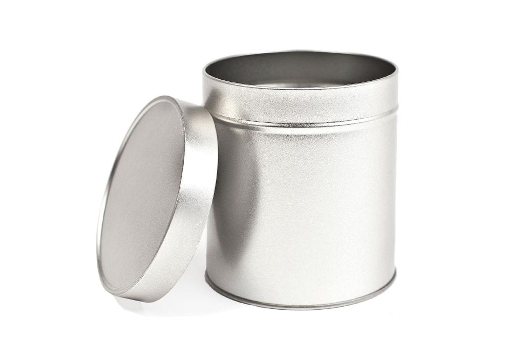 Boîte à pain d'épices ronde ouverte en métal de couleur argentée avec couvercle emboîtant retiré, présentée sur fond blanc.
