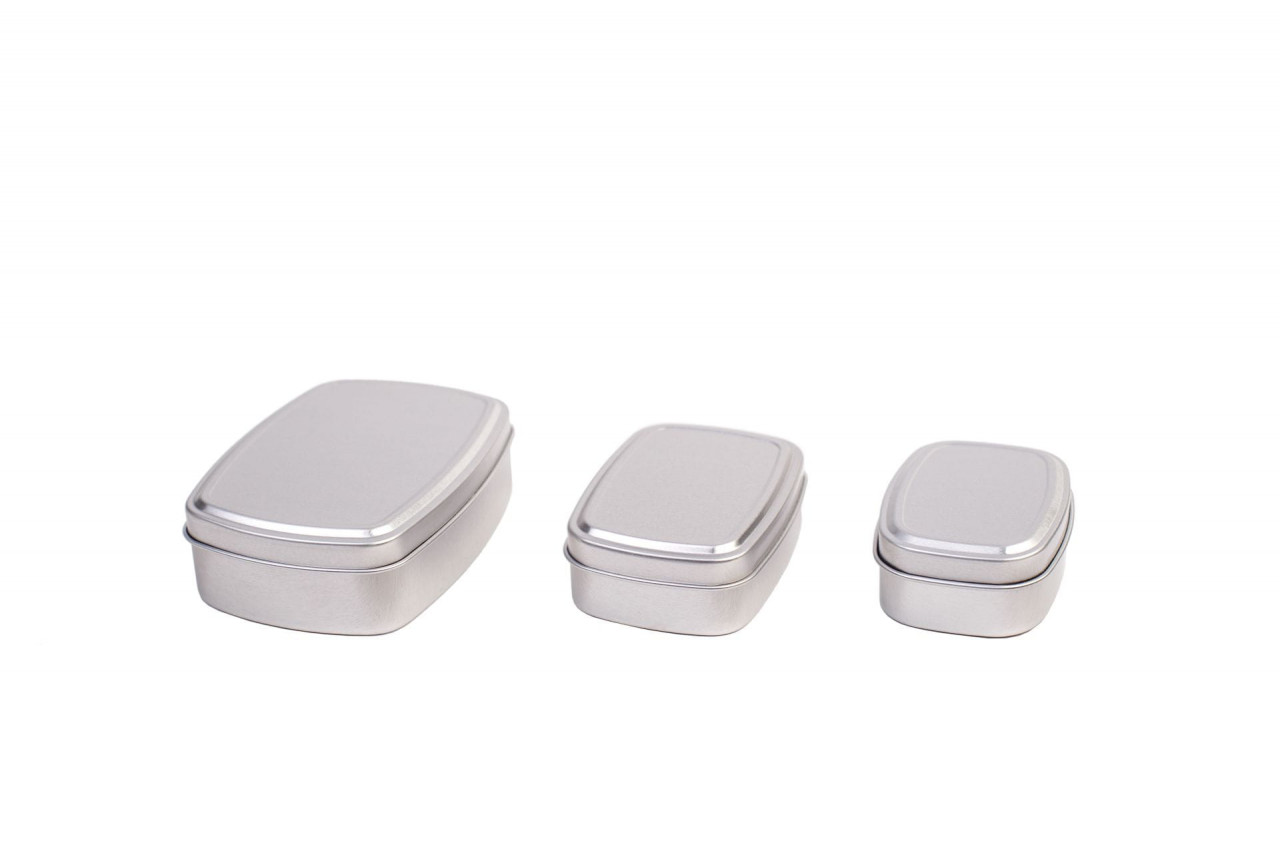 Trois boîtes angulaires fermées en aluminium argenté avec couvercles emboîtants de différentes tailles, disposées côte à côte sur fond blanc.