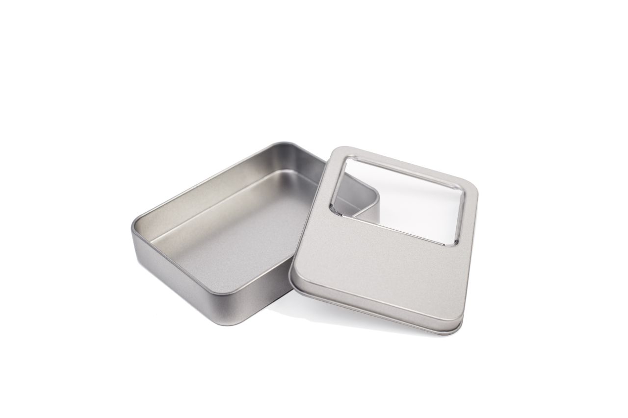 Petite boîte métallique ouverte en métal couleur argent avec couvercle amovible présentant une fenêtre de visualisation rectangulaire, photographiée sur fond blanc.